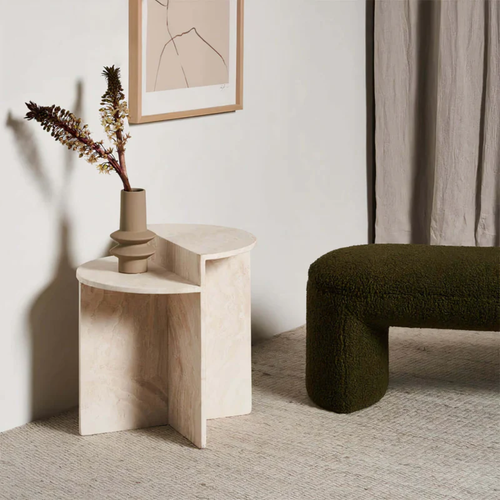 White Stone Side Table With Geometric Base with a vase of flowers next to a green sofa in a minimalistic room.