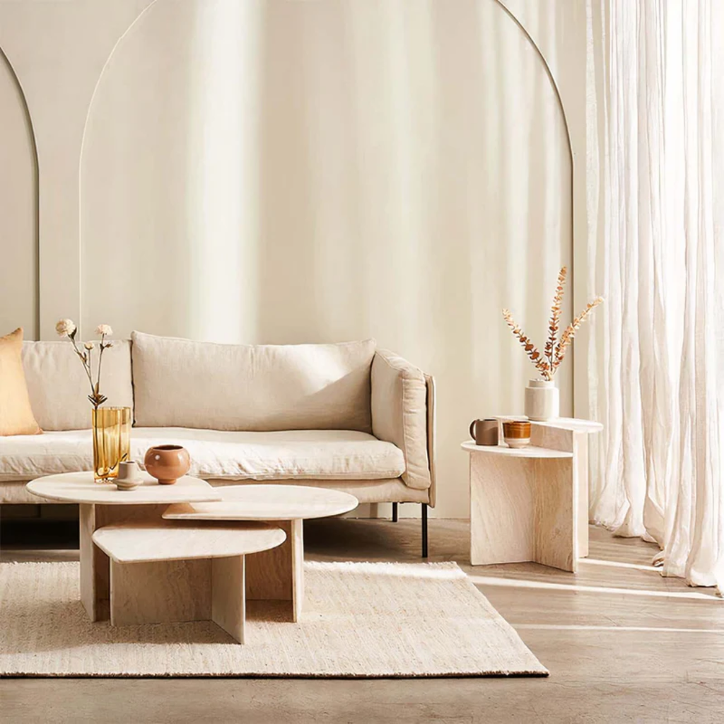 Modern living room with beige sofa, White Stone Side Table With Geometric Base, and decorative elements.