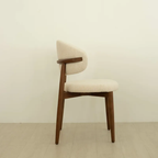Beige chair with wooden frame on a light wooden floor and white wall background