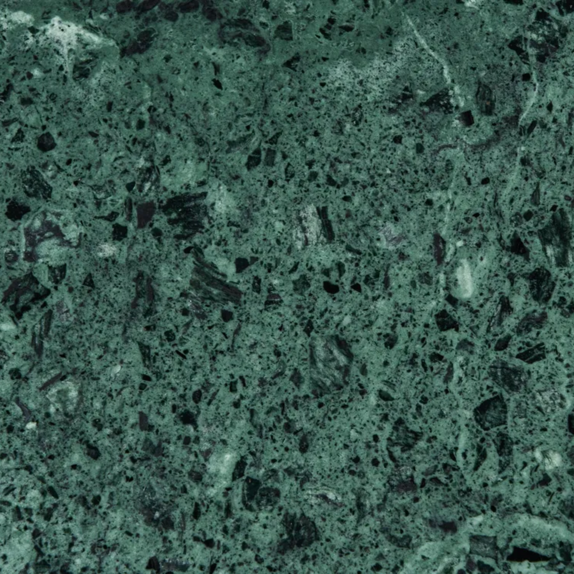 A close-up of a speckled green stone or marble-like surface with dark flecks and lighter green variation, filling the frame.