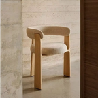 Cream Fabric And Oak Dining Chair with wooden legs against a textured wall.
