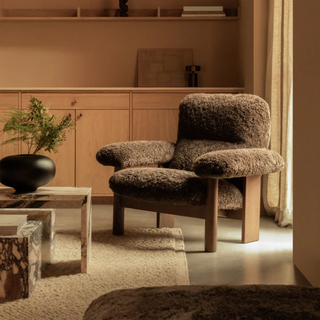 Brown textured armchair in a living room setting with wooden cabinets and a rug.