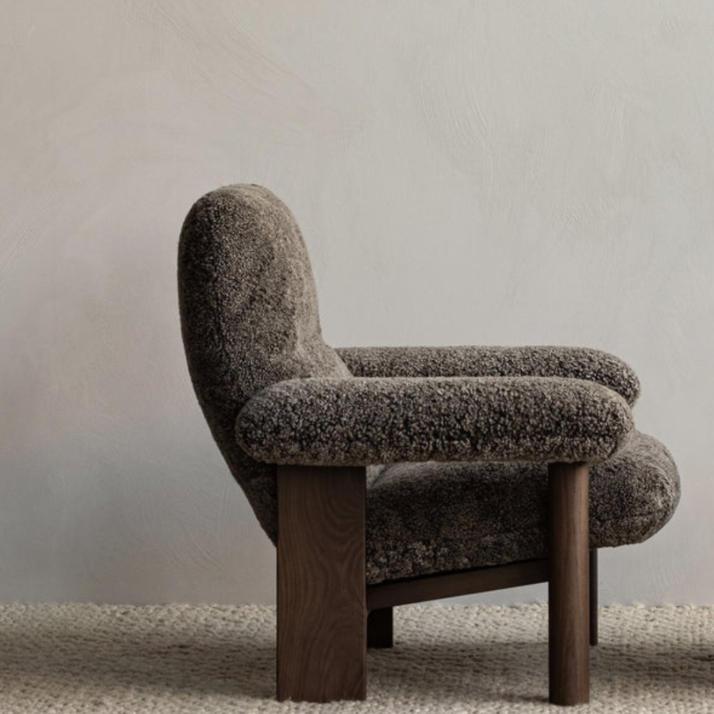 Brown textured armchair with wooden legs on a neutral background
