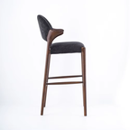 Bar stool with dark gray cushioned seat and backrest on a white background