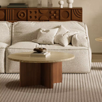 Beige sofa with decorative pillows and a Round Travertine Coffee Table in a living room setting.