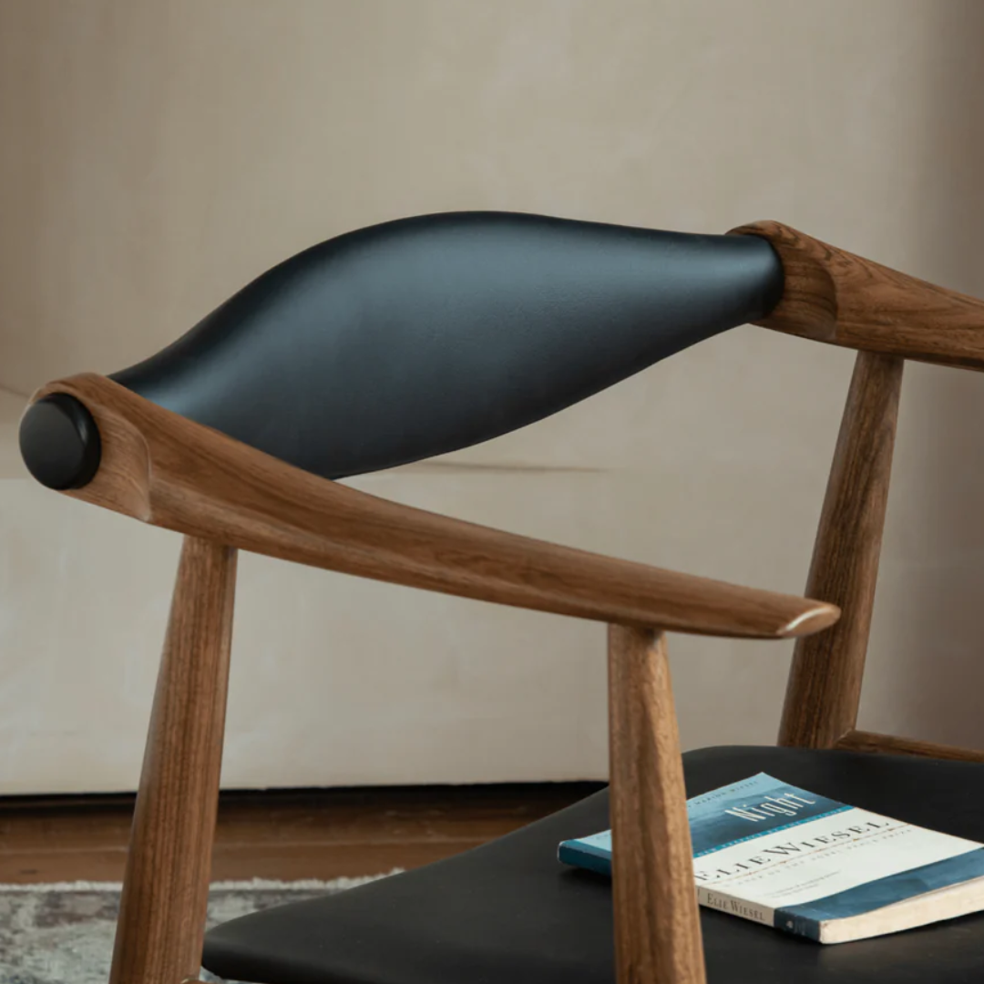 Wooden chair with black cushion on a neutral background clos up