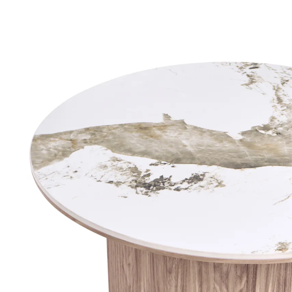 Close-up of a round table top with a white and beige marble pattern and a light wood pedestal base, shown on a white background.