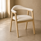 A modern wooden dining chair with a curved backrest and armrests, upholstered in a textured cream bouclé fabric, set in a minimalist beige room.