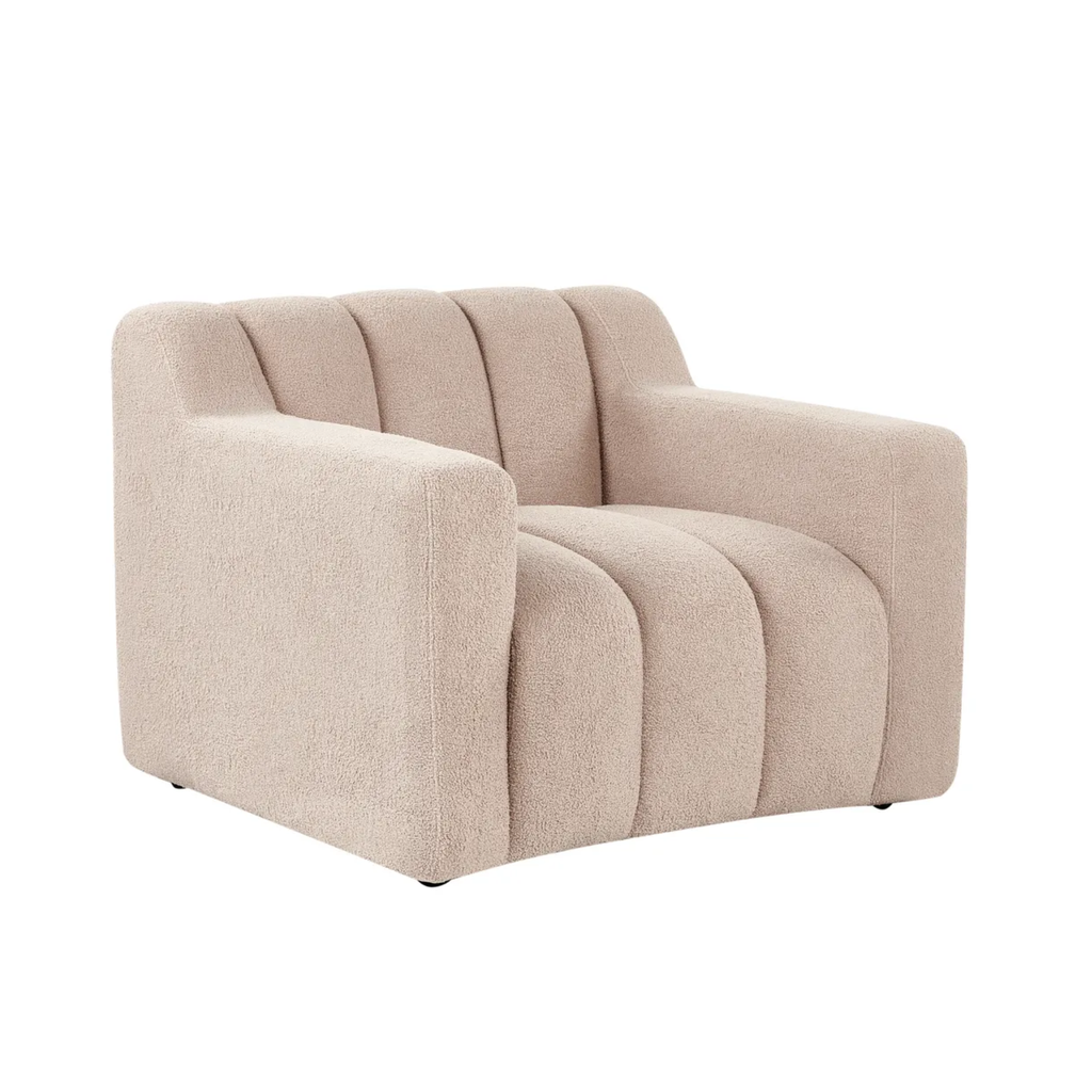 A modern armchair upholstered in a textured beige bouclé fabric, featuring vertical channel tufting on the backrest and seat, set against a plain white background.