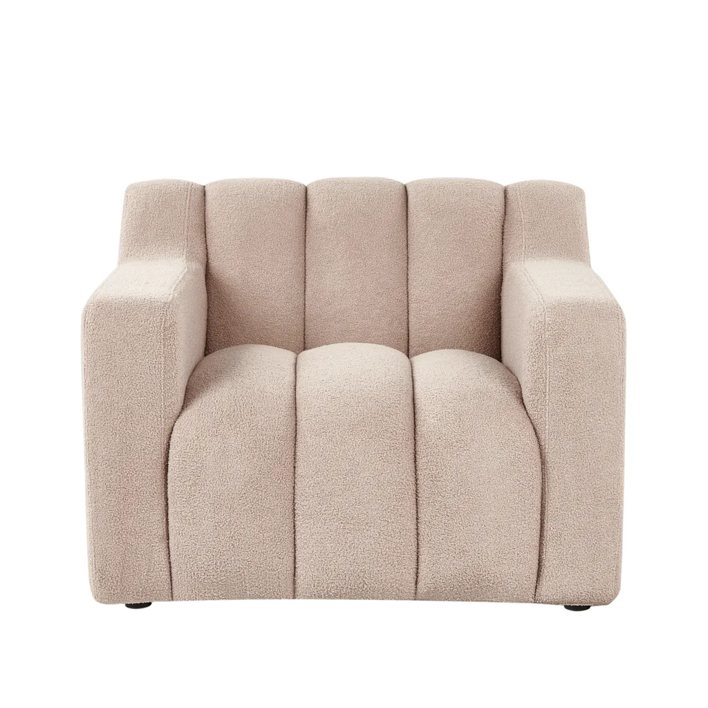 A modern upholstered armchair with a textured bouclé fabric in a light beige color, featuring vertical channel tufting on the backrest and seat, set against a plain white background.