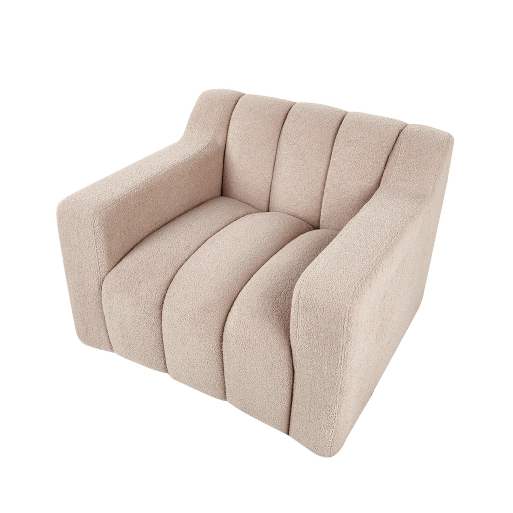 A modern low-profile armchair upholstered in a textured light beige fabric, featuring vertical channel tufting on the backrest and seat, set against a plain white background.