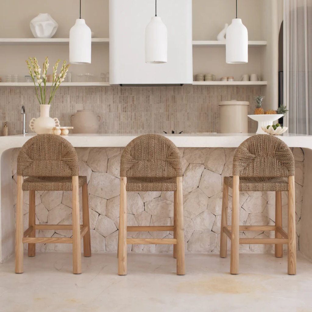 Three wooden bar stools with woven seats in a modern kitchen.