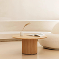 Oak Round Coffee Table with Fluted Base with a vase and book in a minimalistic living room.