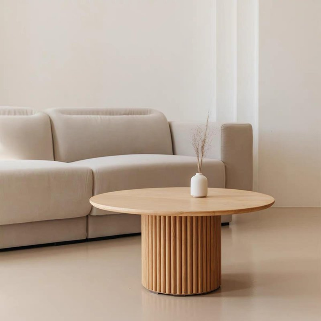 Beige sofa with a Oak Round Coffee Table with Fluted Base and a vase in a minimalistic living room.