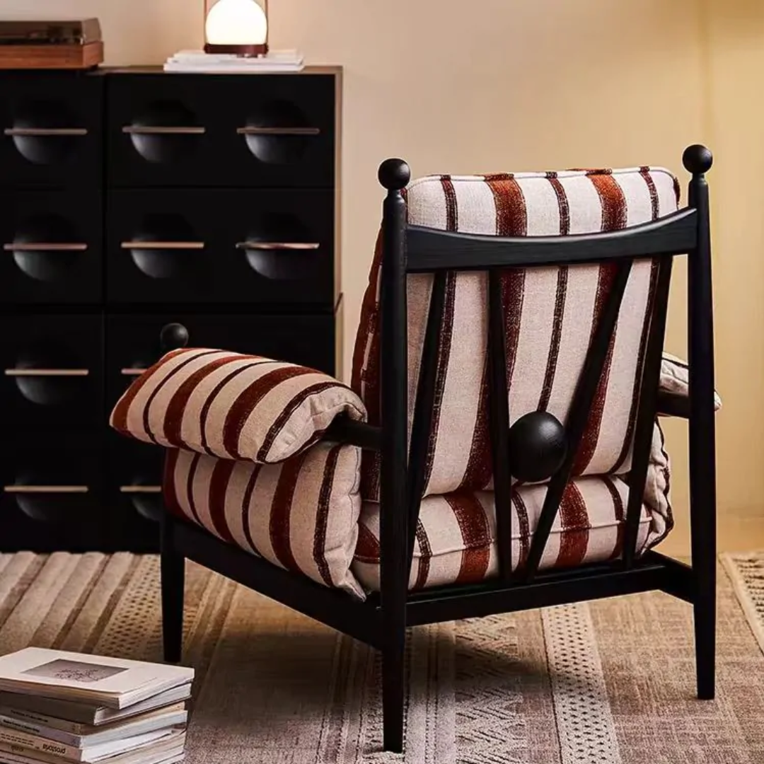 red pinstriped armchair  with striped cushions in a room setting with a dresser and books.