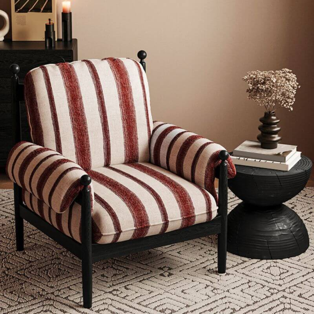 red pinstriped armchair in a room with a side table and decorative items.