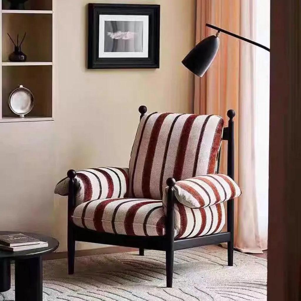 red pinstriped armchair in a living room setting with a lamp and decor items.