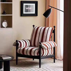 red pinstriped armchair in a living room setting with a lamp and decor items.