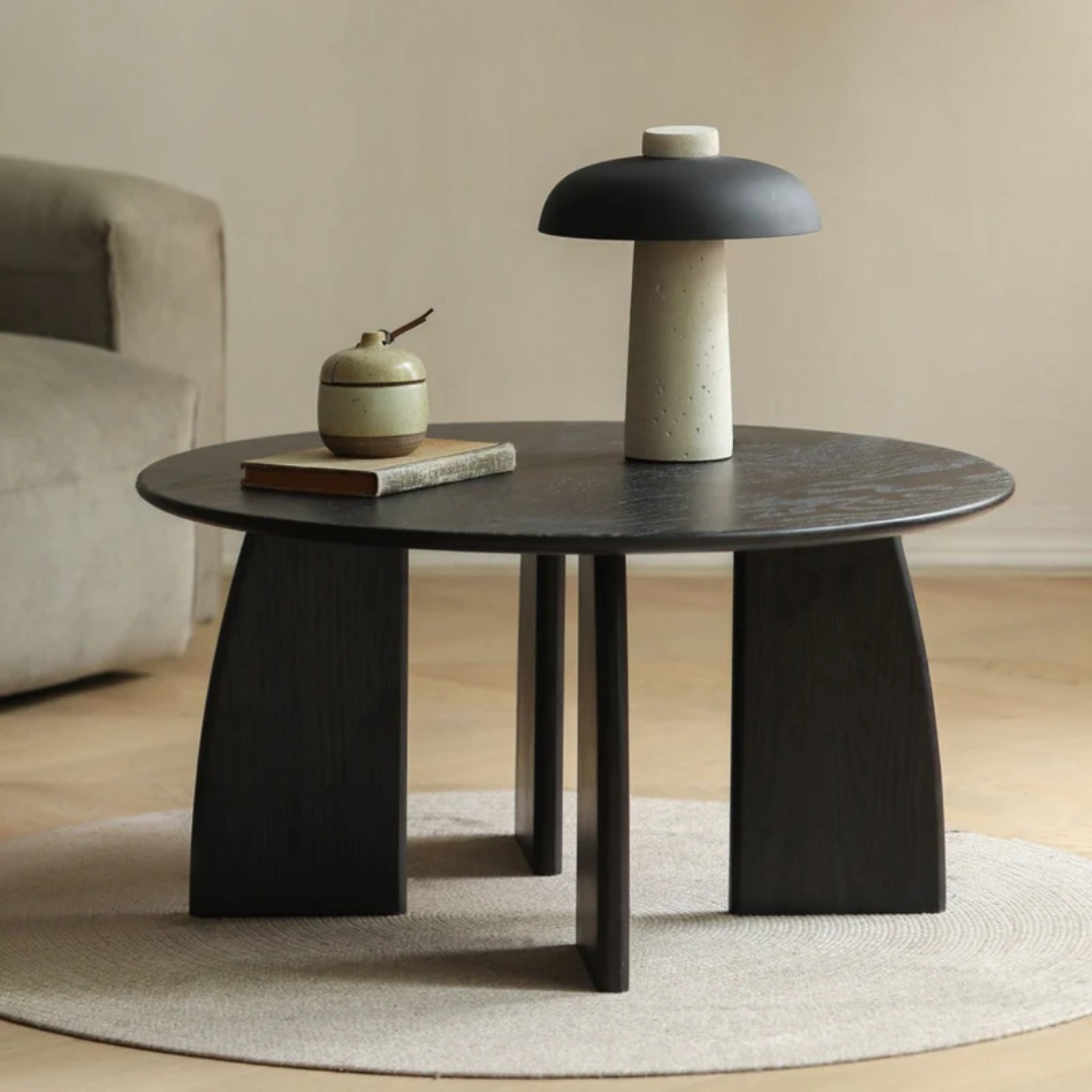 Modern black coffee table with a lamp and decorative items in a minimalistic room.