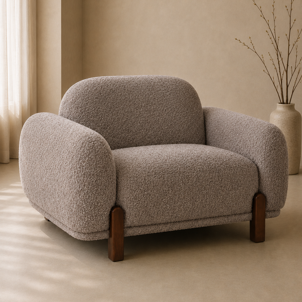 A modern low-profile armchair upholstered in a textured bouclé fabric in a warm taupe-beige color, with dark brown wooden legs, set in a minimalist beige room.