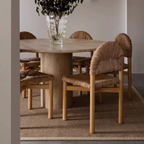 Dining table with woven chairs in a room setting