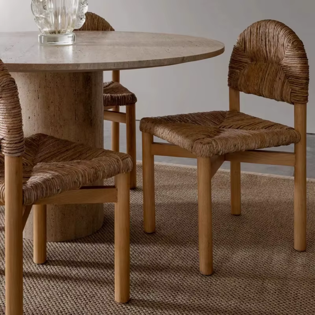 Round wooden dining table with four  Woven Seat Dining Chairs  on a textured rug.