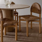 Round wooden dining table with four  Woven Seat Dining Chairs  on a textured rug.