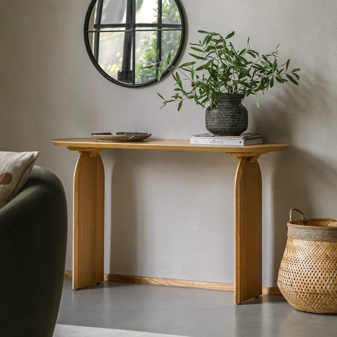  Sculptural Oak Hall Console Table with a plant and books against a gray wall.