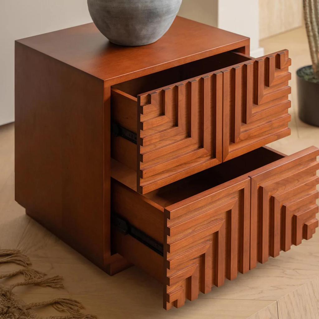 Wooden side table with geometric design on drawers in a room setting