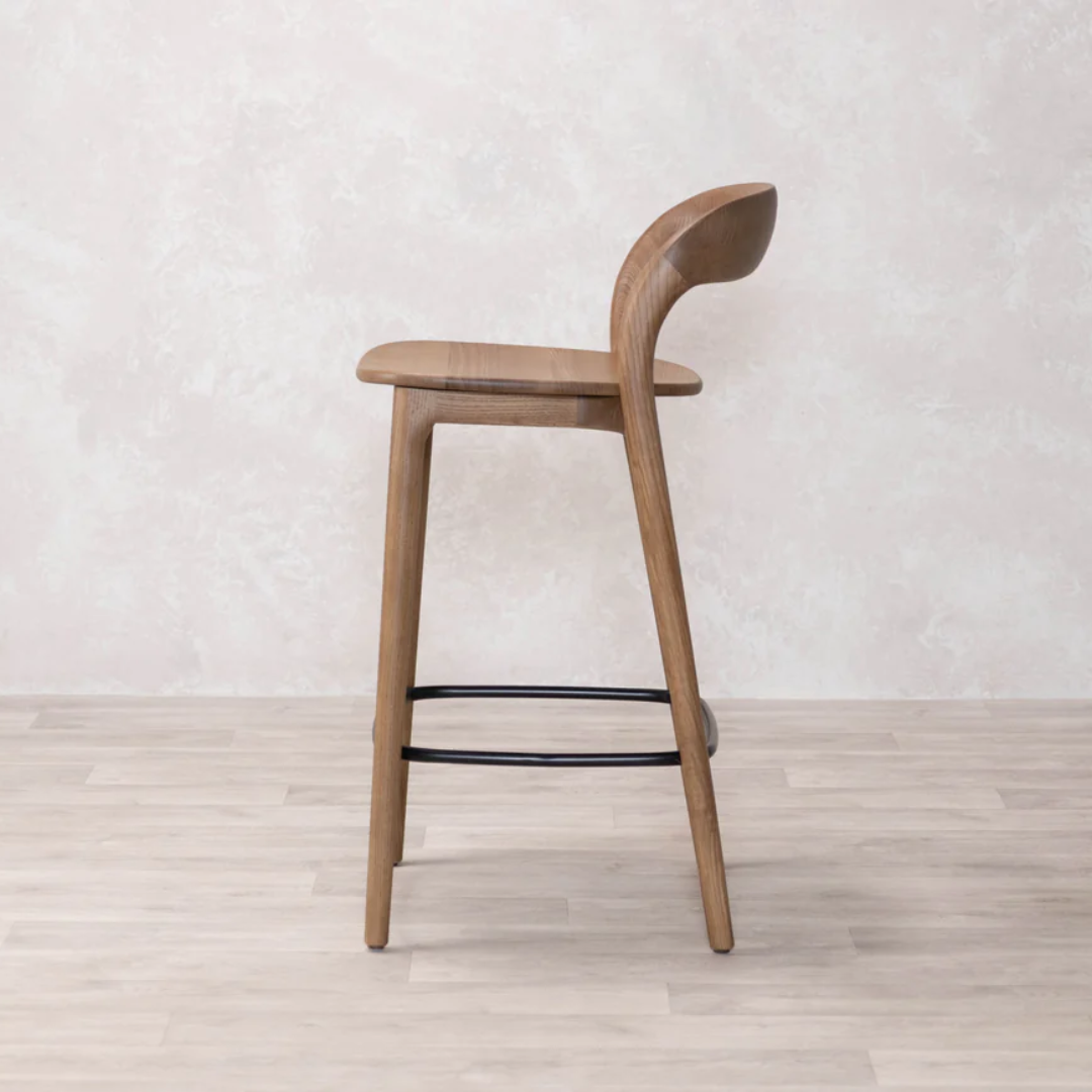Wood Counter Stools With Backs against a light gray wall.