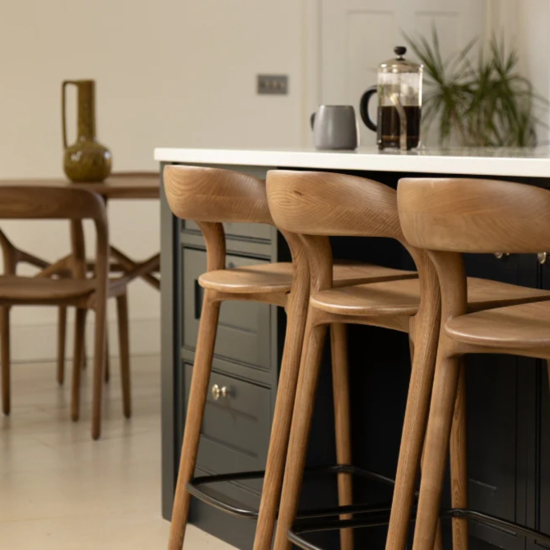 Wooden bar stools in a kitchen setting with a counter and coffee press.