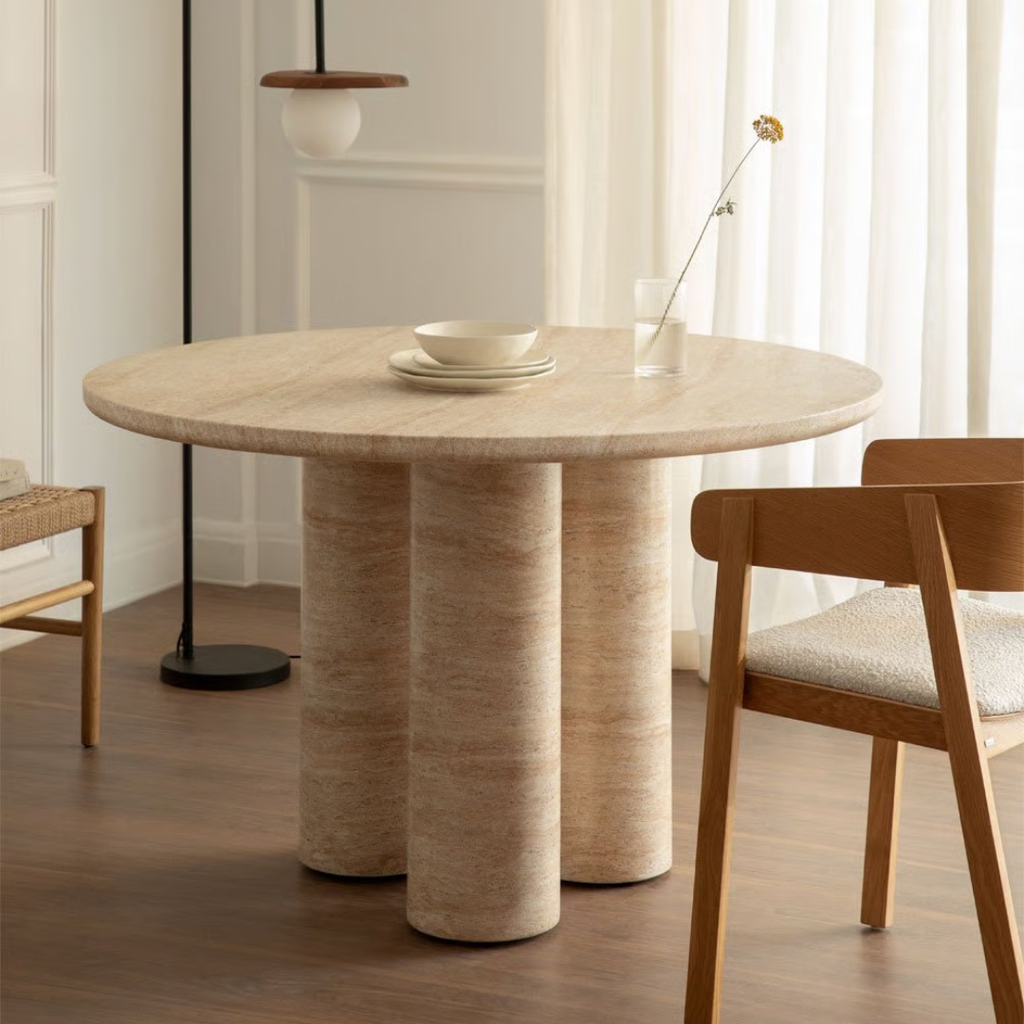 Round Travertine Dining Table with chairs in a room with curtains and a lamp.