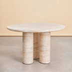 Round stone table with cylindrical legs on a neutral background