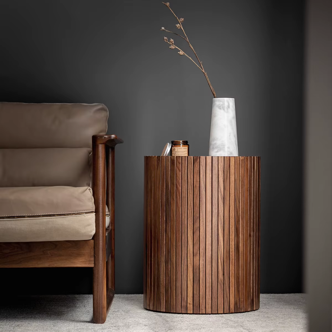Walnut Side Table with Hidden Storage and a vase and books next to a brown armchair against a dark wall.