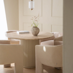 Travertine Dining Room Table with a vase of flowers in a room with beige walls and chairs.