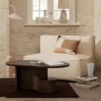 Beige sofa with a  Dark Wood Oval Coffee Table With Sculptural Base and decorative items in a modern living room.