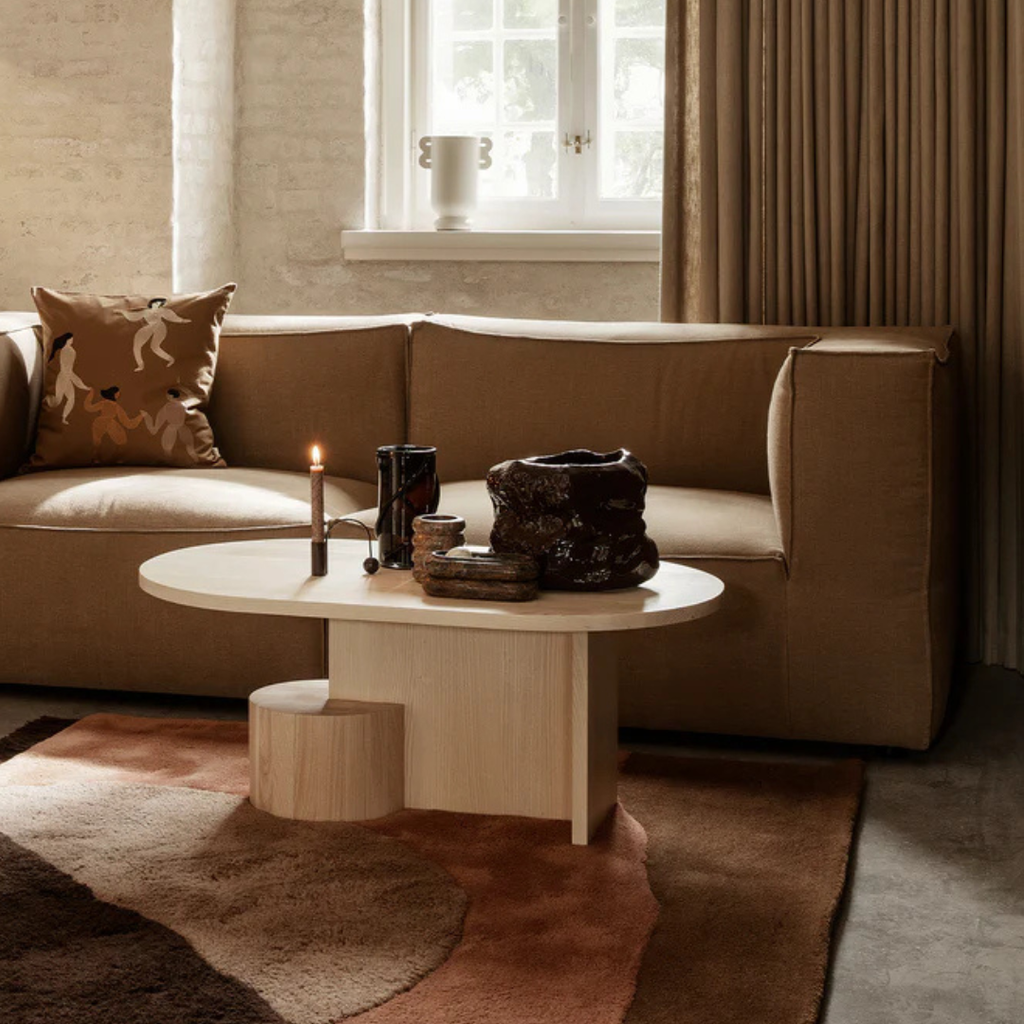 Modern living room with a beige sofa,  light Wood Oval Coffee Table With Sculptural Base, and decorative items.