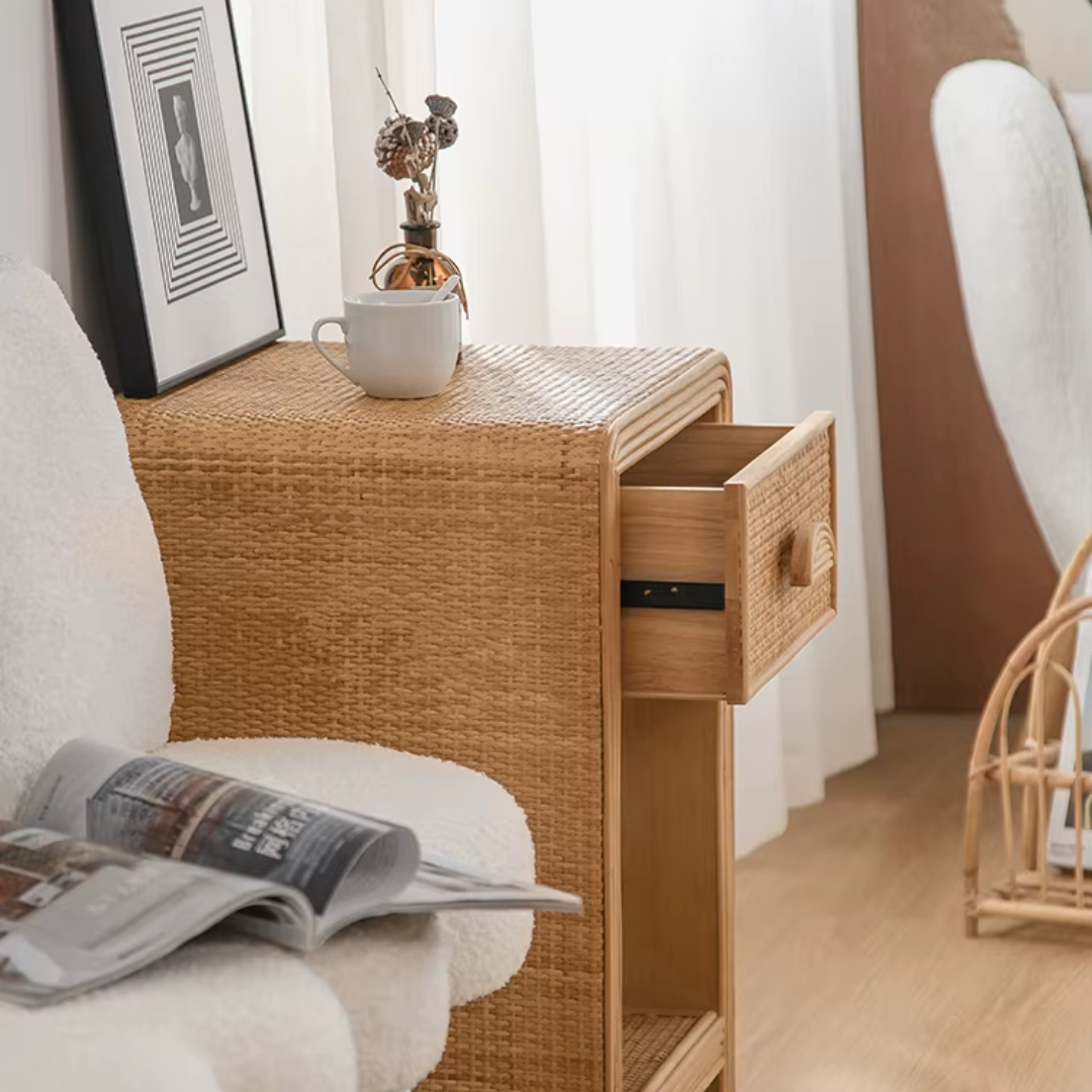 Wicker side table with a drawer, cup, and newspaper in a room setting.