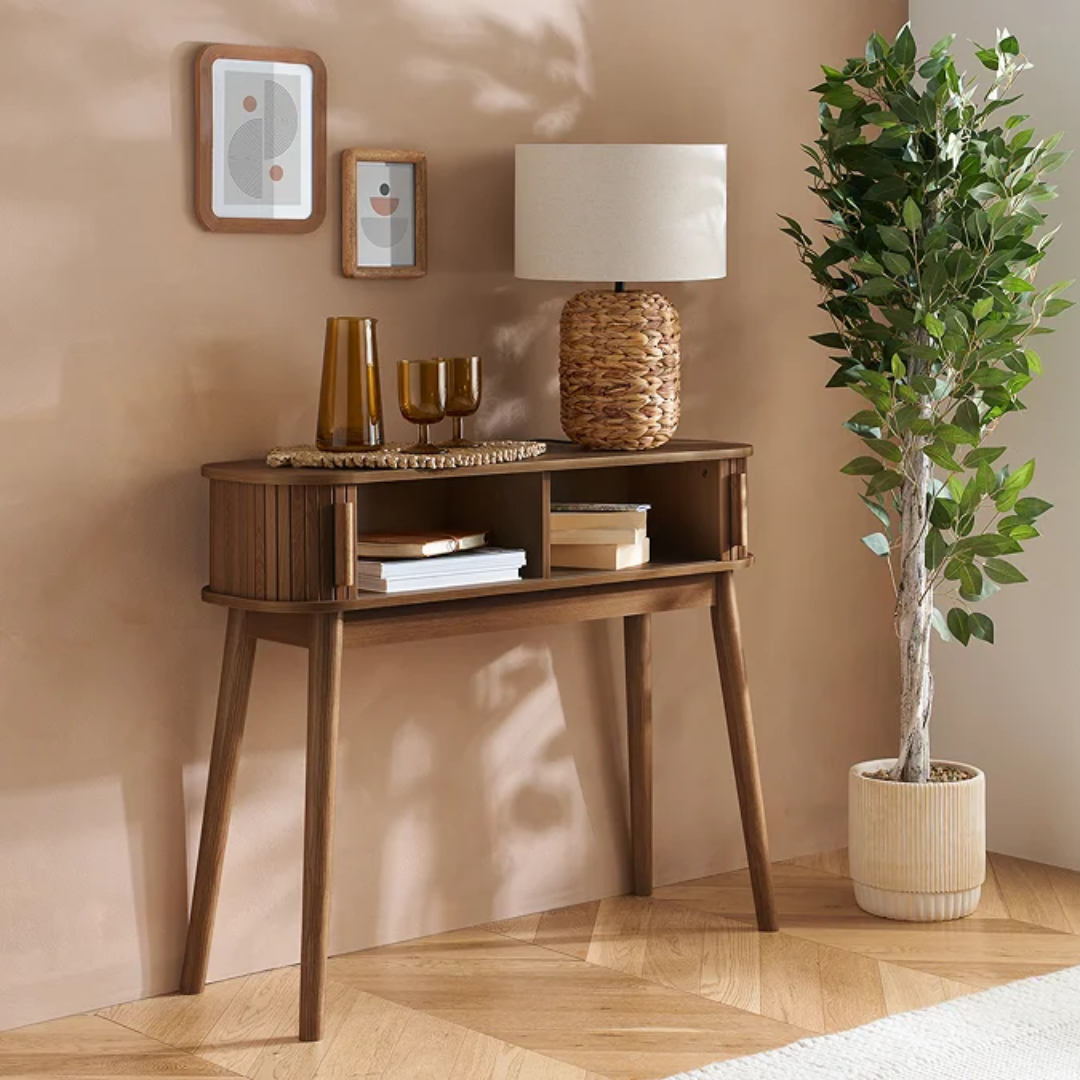 Walnut Narrow Fluted Console Table With Sliding Doors with decorative items against a beige wall