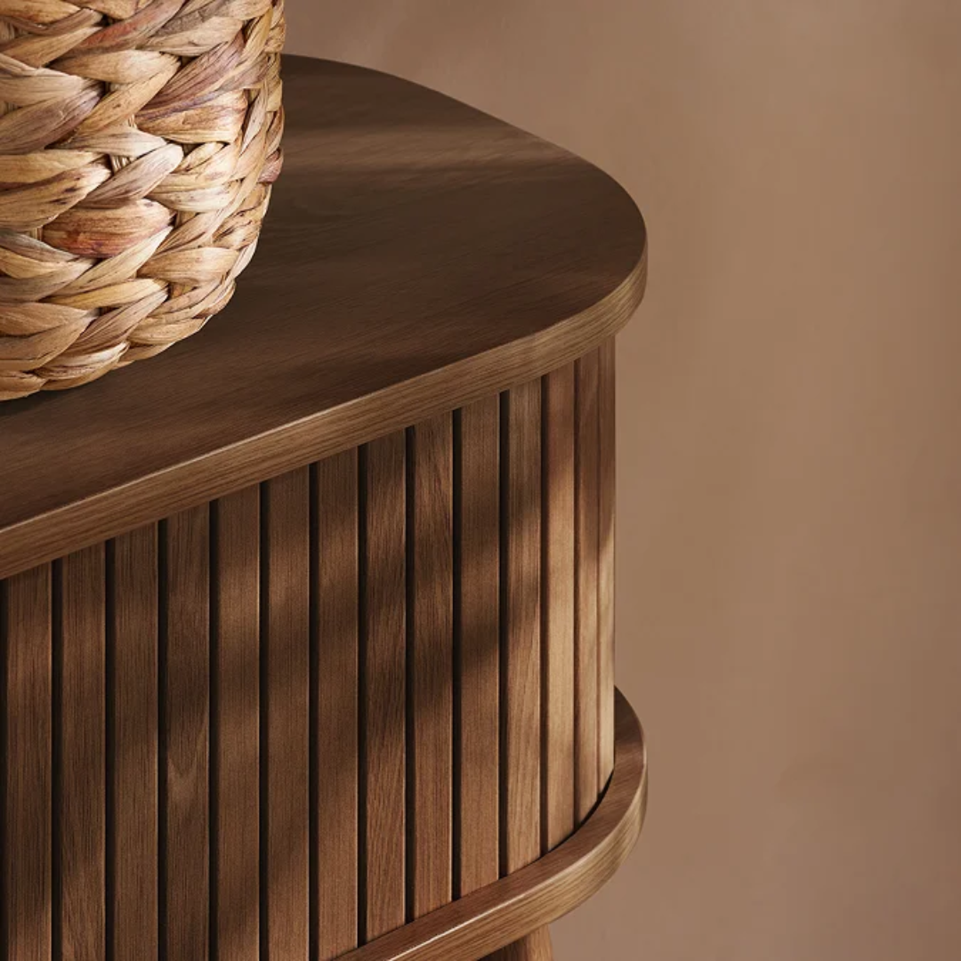 Walnut Narrow Fluted Console Table With Sliding Doors with a woven basket on top against a beige background