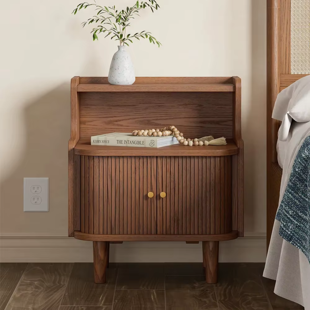 Wooden nightstand with decorative items against a beige wall.