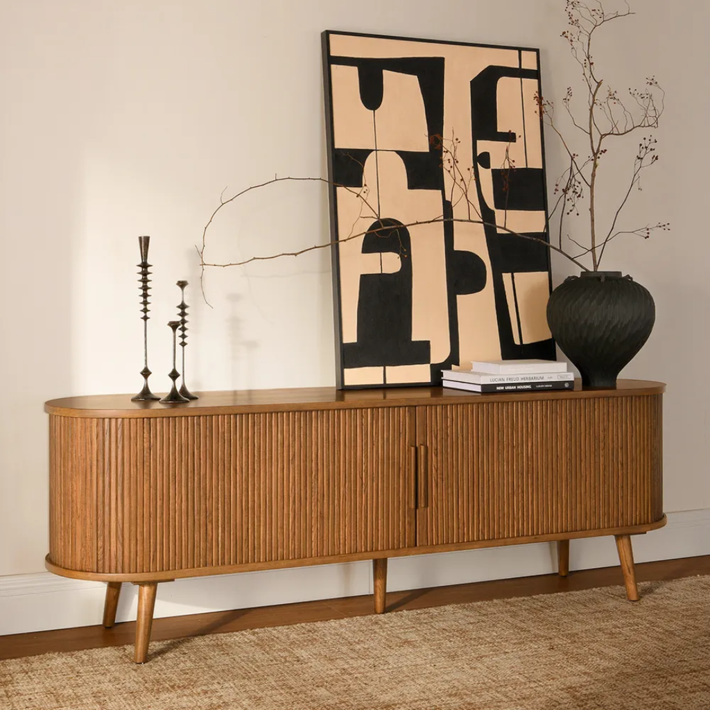 Fluted Walnut TV Unit with Sliding Doors with decorative items against a neutral wall