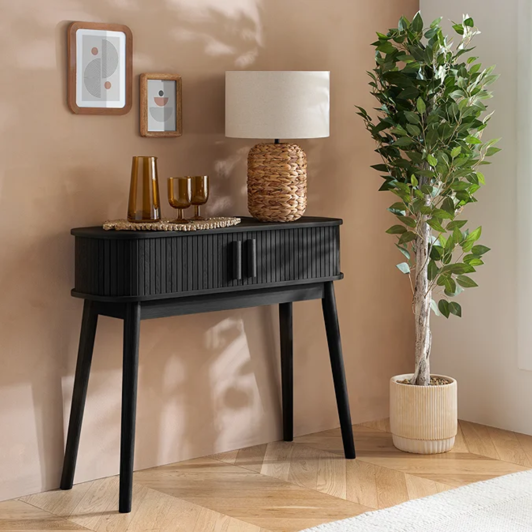 Modern Black Ribbed Console Table  with decorative items against a beige wall