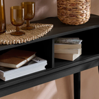 black shelf with books, glasses, and a woven basket on a neutral background