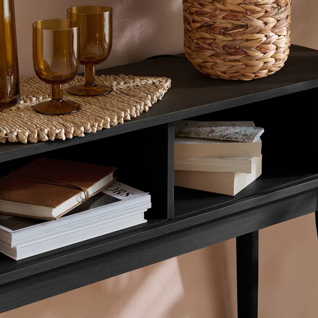 black shelf with books, glasses, and a woven basket on a neutral background